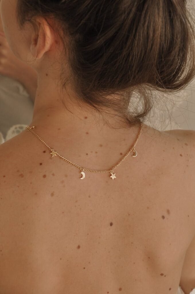 Delicate gold necklace draped on a woman's bare back, enhancing elegance and femininity.